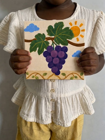 Une enfant tient son tableau de raisins terminé